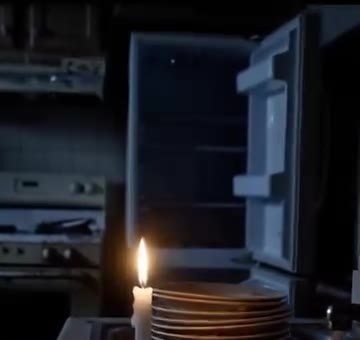 Nevera abierta y apagada, iluminada por una vela